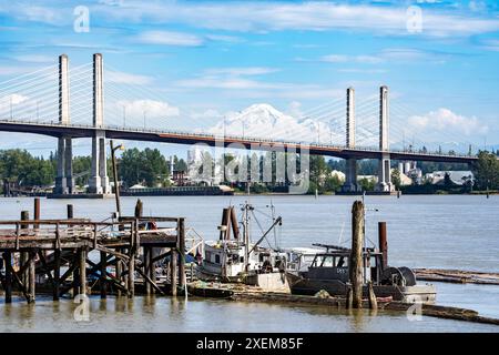 Port Coquitlam Columbia Britannica Canada, 9 giugno 2024: Peschereccio parcheggiato affacciato su un ponte sospeso a cavo con il Monte Baker sullo sfondo. Foto Stock