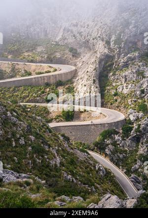 La famosa strada sa Calobra di Maiorca, Spagna, un luogo preferito da tutti i ciclisti. I ciclisti solitari si arrampicano su una strada tortuosa Foto Stock