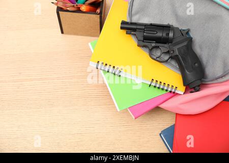 Cancelleria scolastica, pistola e zaino su scrivania in legno, vista dall'alto. Spazio per il testo Foto Stock