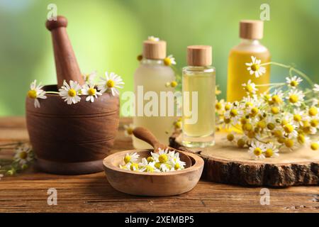 Diversi fiori e bottiglie di oli essenziali su tavola di legno Foto Stock