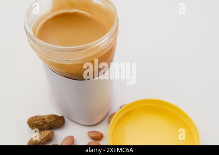 Una foto ravvicinata di una tazza di plastica da una tazza traboccante di crema burro di arachidi Foto Stock