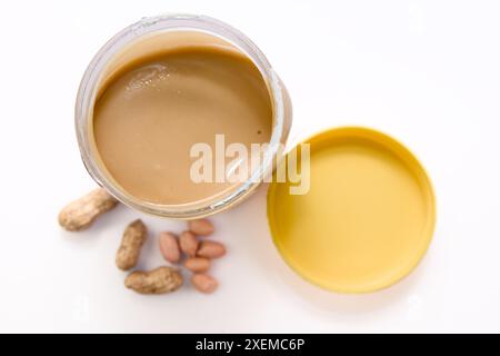 Vista ravvicinata di un vaso di vetro traboccante di delizioso e cremoso burro di arachidi Foto Stock