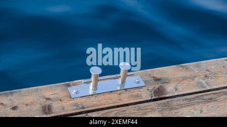 Supporto in metallo per ormeggio barche (dissuasore in acciaio inox) su una piattaforma in legno vicino a un corpo d'acqua. Foto Stock