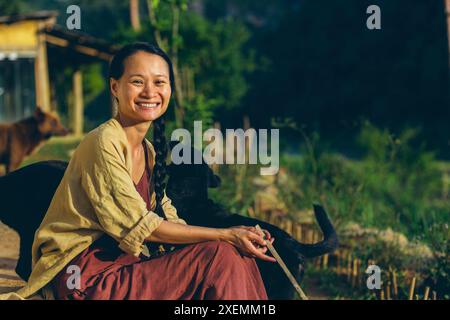 Giovane donna seduta all'aperto accanto al bestiame alla luce del sole, Vietnam; Ngoc Chien, distretto di Muong la, Son la, Vietnam Foto Stock