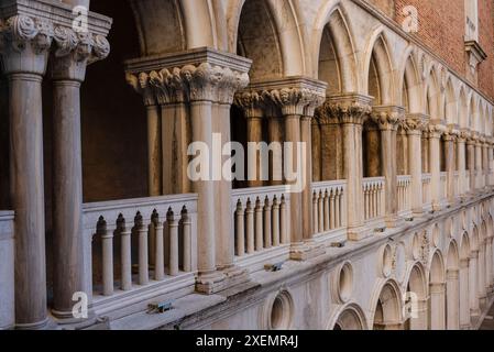 Vista ravvicinata dei lavori decorativi in pietra sulle colonne e gli archi del colonnato con balcone che si affaccia sul cortile del Palazzo Ducale Foto Stock