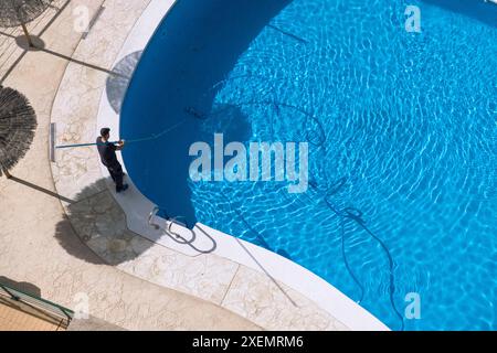 Pulizia e manutenzione della piscina. Vista aerea della persona che si occupa della manutenzione della piscina nelle giornate di sole Foto Stock