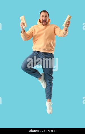 Salta il giovane con un gustoso kebab doner su sfondo blu Foto Stock