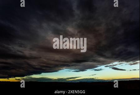 Spettacolari nuvole di tempesta con una pausa nella copertura delle nuvole e il caldo bagliore del tramonto; Calgary, Alberta, Canada Foto Stock