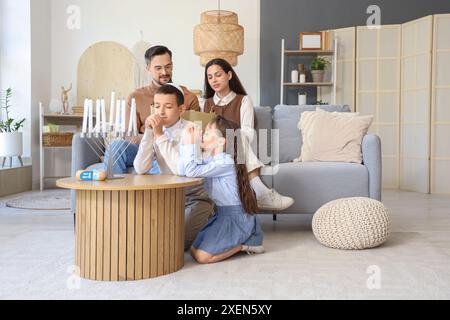 Piccoli bambini ebrei con i loro genitori che pregano a casa Foto Stock