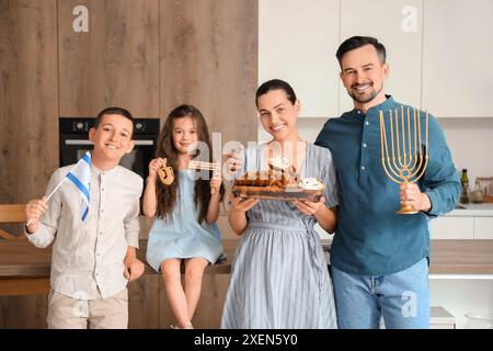 Felice famiglia ebraica con il pane e la bandiera di Israele in cucina Foto Stock