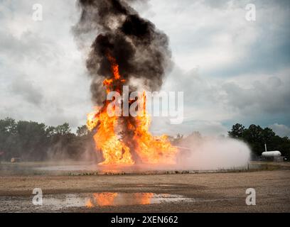 Un addestratore di aerei viene messo in fiamme durante un'esercitazione antincendio presso la Joint base Langley-Eustis, Virginia, il 27 giugno 2024. Questo esercizio non era solo un'opportunità di formazione per il reparto dei vigili del fuoco del 633d Civil Engineer Squadron, ma era anche visto dai cadetti del Junior Reserve Officers' Training Corps provenienti da oltre otto distretti scolastici. Questa dinamica ha evidenziato l’importanza dell’impegno comunitario e della cooperazione militare coinvolgendo gli studenti di Hampton Roads. (Foto U.S. Air Force del Senior Airman Mikaela Smith) Foto Stock