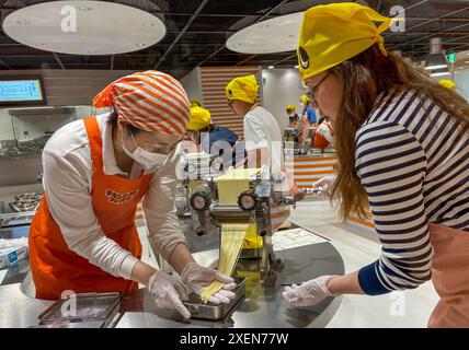 Un visitatore ha visto arrotolare l'impasto dei tagliatelle durante il processo di produzione dei tagliatelle istantanei al CupNoodles Museum. Il museo è dedicato alla storia degli spaghetti istantanei e alla storia di Nissin Foods, fondata da Momofuku Ando, l'inventore degli spaghetti istantanei e dei CupNoodles. Il museo ha due sedi, una a Osaka e l'altra a Yokohama, in Giappone. Foto Stock