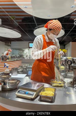 Un membro del personale del CupNoodles Museum controlla i noodles durante il processo di produzione dei noodles istantanei e cerca di creare i propri spaghetti istantanei personalizzati. Il museo è dedicato alla storia degli spaghetti istantanei e alla storia di Nissin Foods, fondata da Momofuku Ando, l'inventore degli spaghetti istantanei e dei CupNoodles. Il museo ha due sedi, una a Osaka e l'altra a Yokohama, in Giappone. Foto Stock