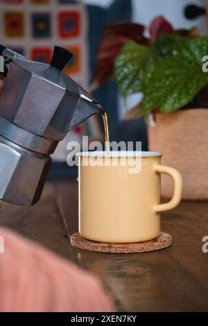 Versare il caffè da una moka in una tazza di smalto Foto Stock