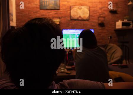 Coppia che guarda una partita di calcio in TV in salotto. Foto Stock