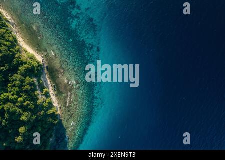 Vista direttamente sopra il Parco Nazionale di Kepulauan Togean, con acqua blu brillante dell'oceano e lussureggiante vegetazione verde, nel Sulawesi centrale, Indonesia Foto Stock