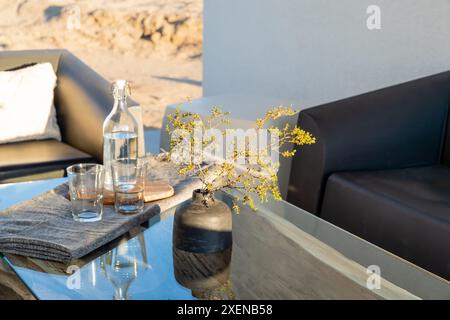 Moderno tavolo all'aperto con bicchieri da bottiglia d'acqua e vaso a Joshua Tree, California Foto Stock