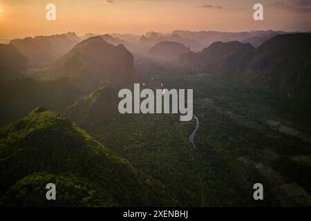 La luce del tramonto sull'aspro paesaggio con formazioni carsiche di pietra calcarea e un fiume che si snoda attraverso la valle nella zona di Thakhek del Laos Foto Stock