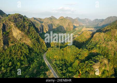 Paesaggio aspro e strada nella valle tra formazioni carsiche calcaree nella zona di Thakhek del Laos; Thakhek, provincia di Khammouane, Laos Foto Stock