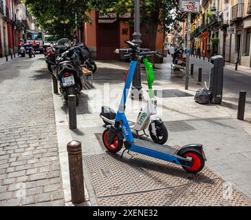 06.19.2024, Madrid, Spagna: Scooter elettrici a noleggio Dott e a Lime parcheggiati in una strada nel centro della città Foto Stock