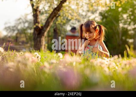 Bambina in giardino con margherite. Quattro-anno-vecchia ragazza su una soleggiata giornata estiva su un prato con margherite. Foto Stock