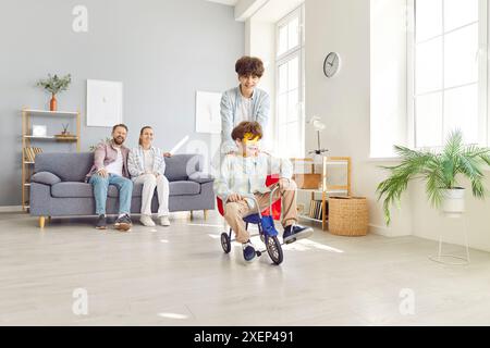 Genitori e bambini che trascorrono il tempo libero e il triciclo Sons Riding a casa Foto Stock