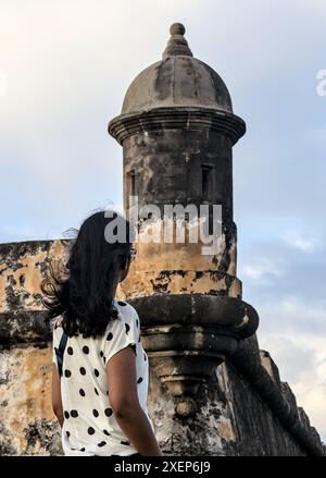 donna che guarda la torre del bastione nel forte del castello di castillo san felipe del morro a san juan porto rico (guardando lontano dalla macchina fotografica, senza volto, irriconoscibile Foto Stock