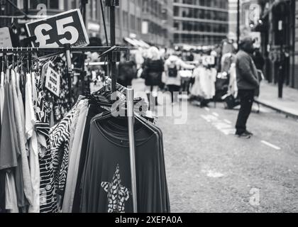 Gli amanti dello shopping sono alla ricerca di occasioni in un mercato di Londra Foto Stock