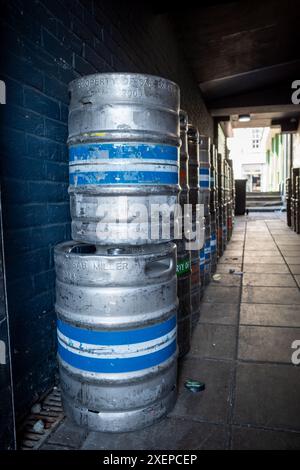 Vicolo stretto tra due edifici con botti di birra vuote impilate Foto Stock