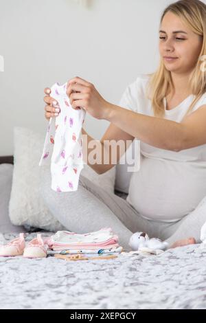 Una donna incinta raccoglie le cose del bambino. Messa a fuoco selettiva. Casa. Foto Stock