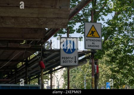 costruzione di un cantiere, passaggio pedonale sotto un ponteggio in un cantiere, i cartelli indicano la direzione e fare attenzione a non inciampare. Foto Stock