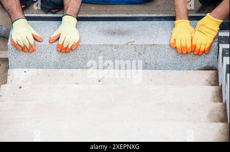 Passi concreti in costruzione come un team di costruttori installare blocchi di cemento pesanti Foto Stock