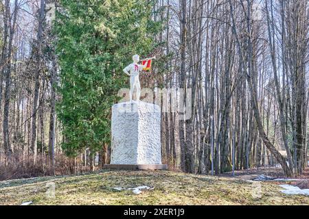 Mosca, Russia - 5 aprile 2024: Scultura del ragazzo pioniere in cravatta rossa che soffia il bugle sul piedistallo. Monumento standard dell'epoca sovietica sulla collina nel vecchio parco. Spri Foto Stock