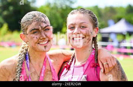 Brighton Regno Unito 29 giugno 2024 - Muddy affronta questi partecipanti dopo aver partecipato all' evento Cancer Research UK Pretty Muddy Race for Life in una calda giornata di sole a Stanmer Park Brighton . I partecipanti che sono stati toccati dal cancro si fanno strada intorno al percorso a ostacoli Pretty Muddy che è poco più di 3 miglia e aiuta a raccogliere migliaia di sterline per Cancer Research UK : Credit Simon Dack / Alamy Live News Foto Stock