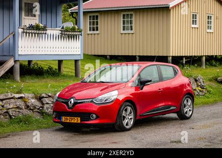 KINSARVIK, NORVEGIA - 13 AGOSTO 2016: Auto rossa Renault Clio Furt nel paesaggio norvegese e case Foto Stock