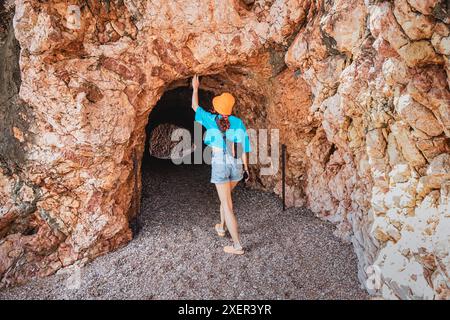 Una donna che esplora una grotta costiera in Montenegro, mescolando antiche formazioni rocciose con splendide viste sul mare e paesaggi aspri. Foto Stock