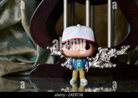 Funko Pop action figure di Dustin Henderson della popolare serie TV di Netflix Stranger Things. Pavimento riflettente, tenda verde, gabbia vintage, colonne. Foto Stock