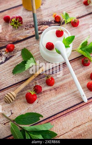 yogurt dolce fatto in casa in barattolo con fragole, su un tavolo di legno. Foto Stock