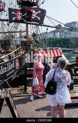 I turisti posano per una foto accanto alla replica del Golden Hind di Sir Francis Drake a Brixham Harbour, Devon. Foto Stock