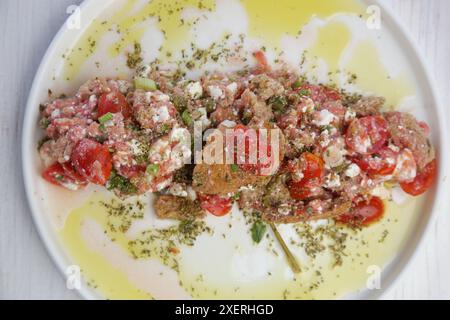 Tradizionale insalata estiva cretese - bagel all'orzo con pomodori grattugiati, formaggio feta e olio d'oliva vergine Foto Stock