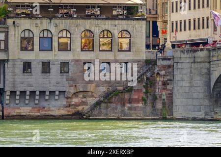 Città di Basilea - Un ponte attraversa il fiume Reno con una città sullo sfondo. Il ponte è una struttura in pietra con un cartello rosso e bianco su di esso. La città è fil Foto Stock