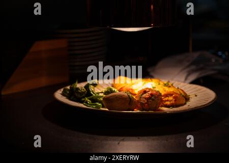 Un piatto di cibo con una luce che splende sopra. Il piatto contiene una varietà di alimenti, tra cui carne, verdure e patate. La luce che splende sulla p Foto Stock