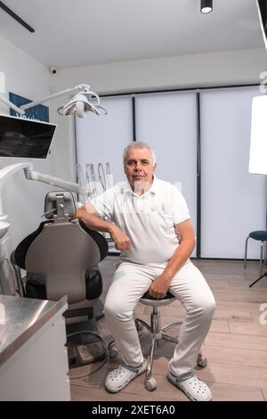 Un dentista attento e attento a un'atmosfera lavorativa positiva è pronto a prendersi cura di tutti gli aspetti del trattamento e della consultazione dei suoi pazienti. Foto Stock