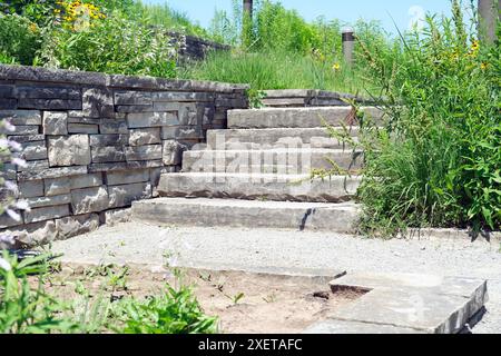 Elegante e lussuoso paesaggio con pareti di contenimento in pietra naturale e trecce, ampi gradini e atterraggio in un giardino naturale di farfalle. Foto Stock