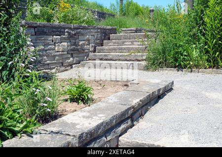 Elegante e lussuoso paesaggio con pareti di contenimento in pietra naturale e trecce, ampi gradini e atterraggio in un giardino naturale di farfalle. Foto Stock