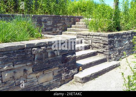 Elegante e lussuoso paesaggio con pareti di contenimento in pietra naturale e trecce, ampi gradini e atterraggio in un giardino naturale di farfalle. Foto Stock