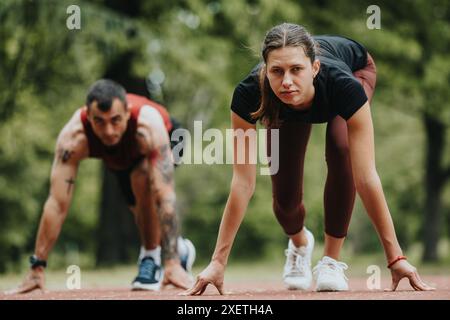 Due amici che si preparano a fare uno sprint in un parco verde lussureggiante, concentrazione e determinazione sono chiari Foto Stock