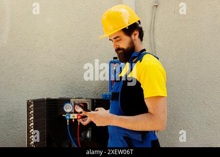 Il riparatore esperto ordina nuovi componenti per il condizionatore d'aria danneggiato dopo aver terminato la manutenzione. Lavoratore esperto che cerca online parti di ricambio per condensatore, assunto dal proprietario dell'azienda Foto Stock