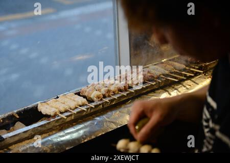 Un giovane giapponese che grigia spiedini al ristorante Washio Yakitori Izakaya a Chuocho, Kagoshima, Giappone. Foto Stock