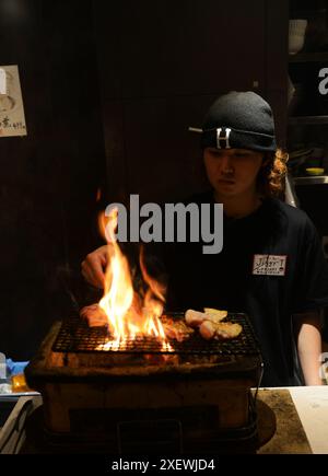 Un giovane giapponese che grigia spiedini al ristorante Washio Yakitori Izakaya a Chuocho, Kagoshima, Giappone. Foto Stock